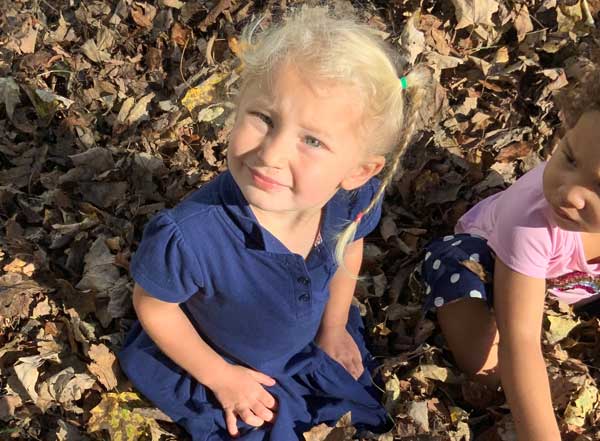 Happy kid playing in autumn leaves